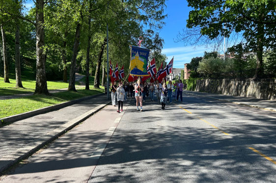 en gruppe mennesker som går nedover en vei med flagg på