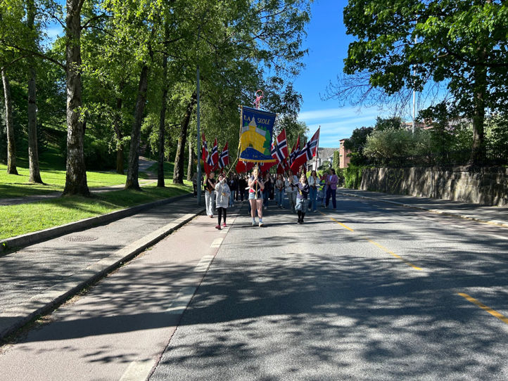 en gruppe mennesker som går nedover en vei med flagg på