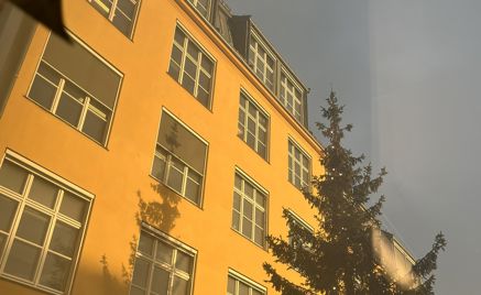 en høy bygning med et tre foran