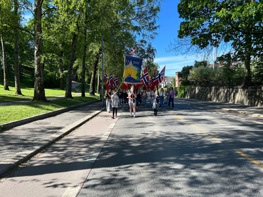 en gruppe mennesker som går nedover en vei med flagg på